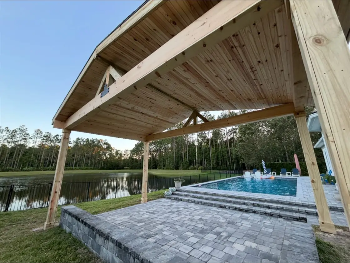 Wood pavilion with a vaulted tongue-and-groove ceiling over a poolside paver patio